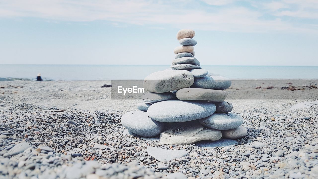 Stack of pebbles at beach against sky