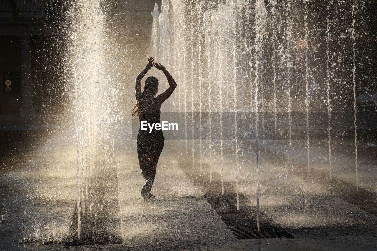 Woman dancing amidst fountain