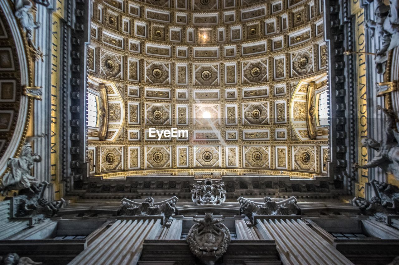 Low angle view of ceiling design in st. peter's basilica, vatican city, italy. gold patterns. 