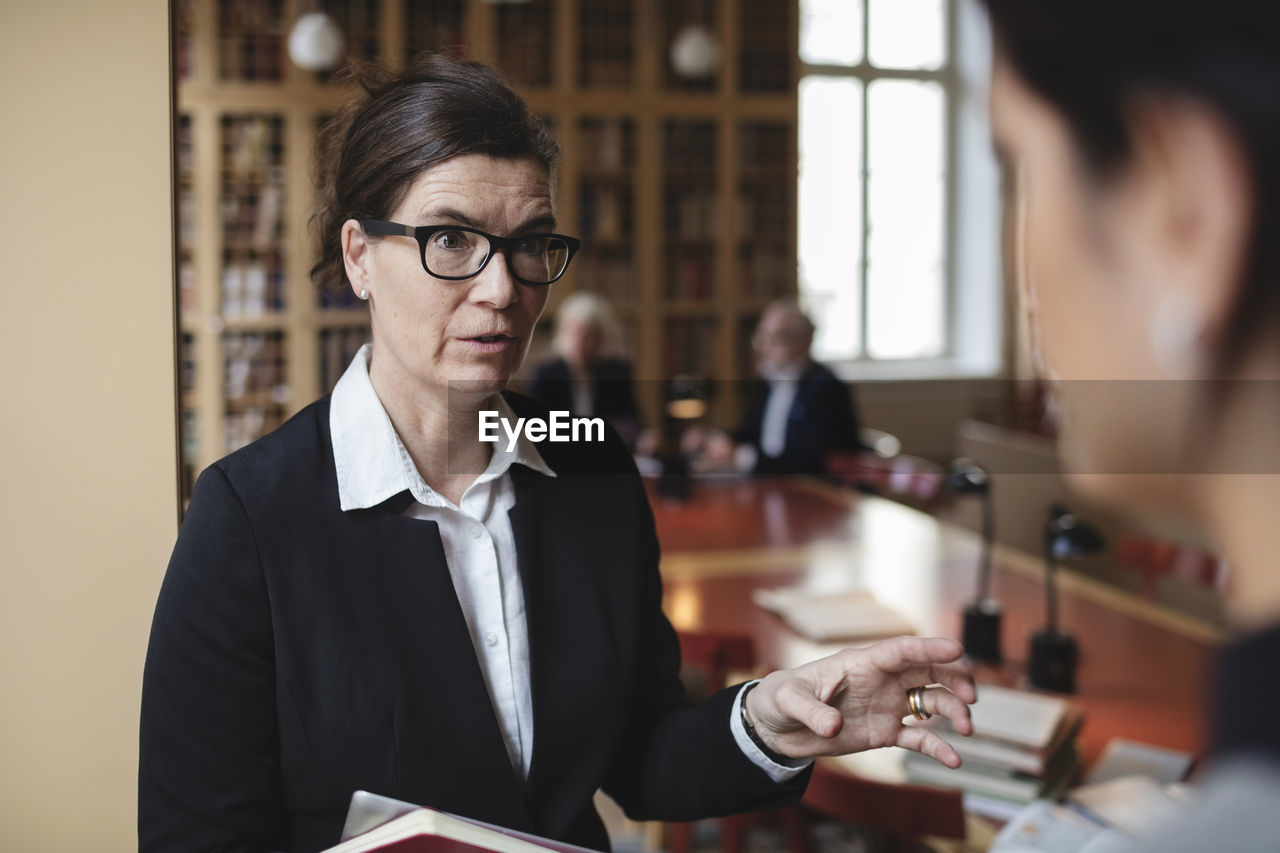 Confident lawyer discussing with female colleague in library