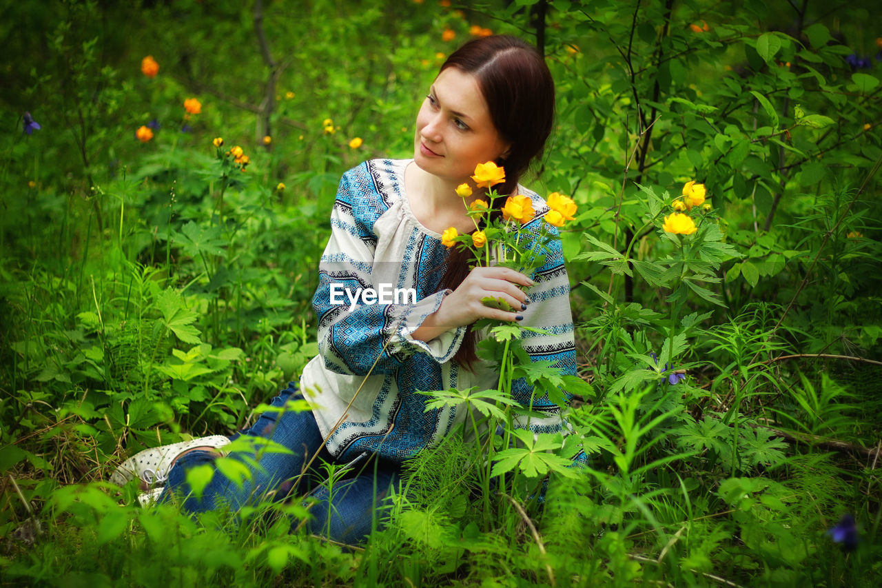 Happy girl holding flower against plants