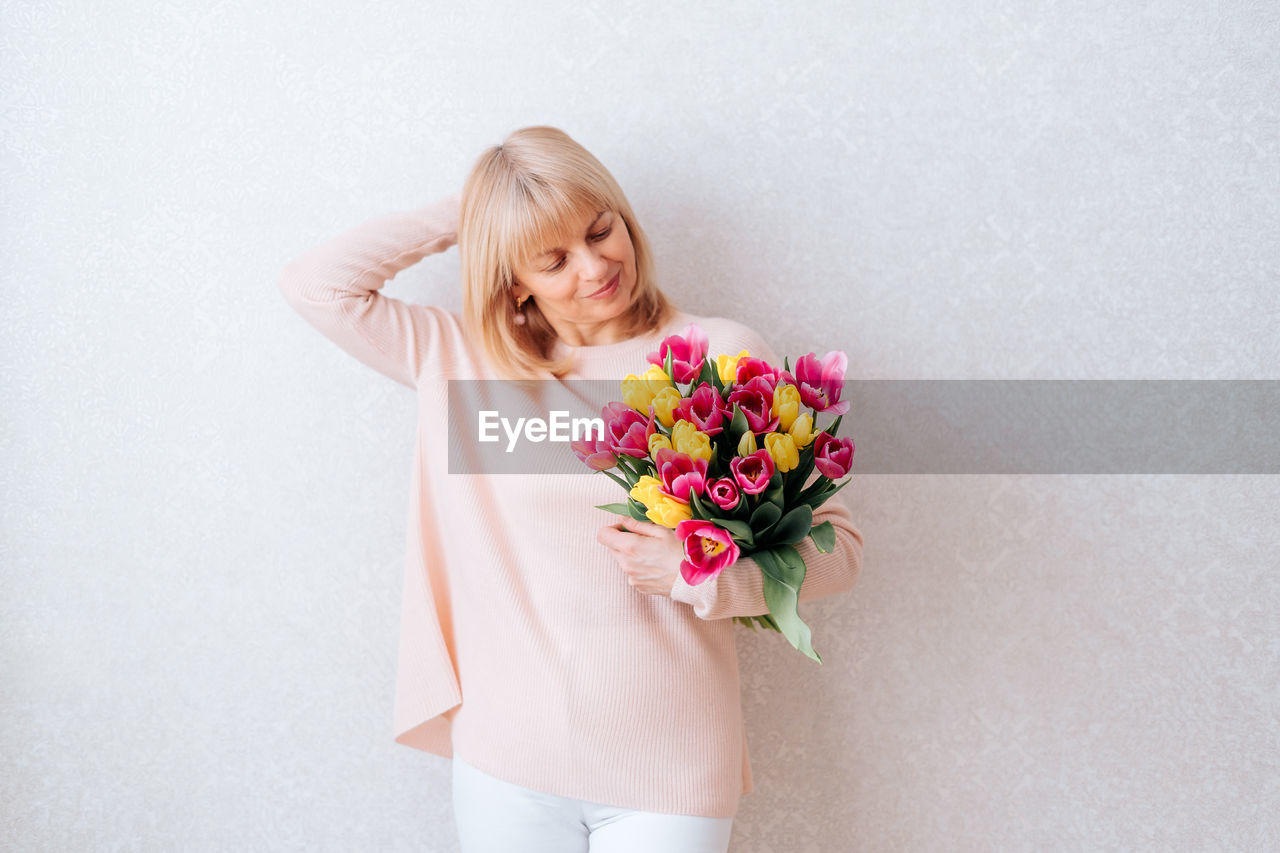 MIDSECTION OF WOMAN HOLDING PINK FLOWER