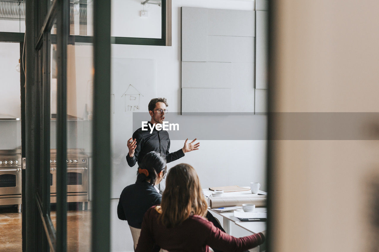 Businessman gesturing during meeting with colleagues in board room at office