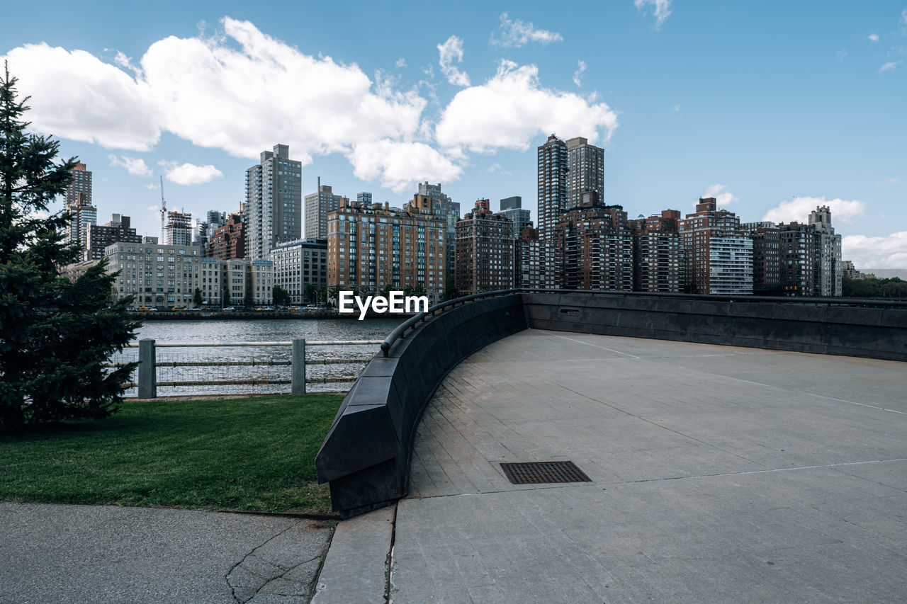 Modern buildings by river against sky in city