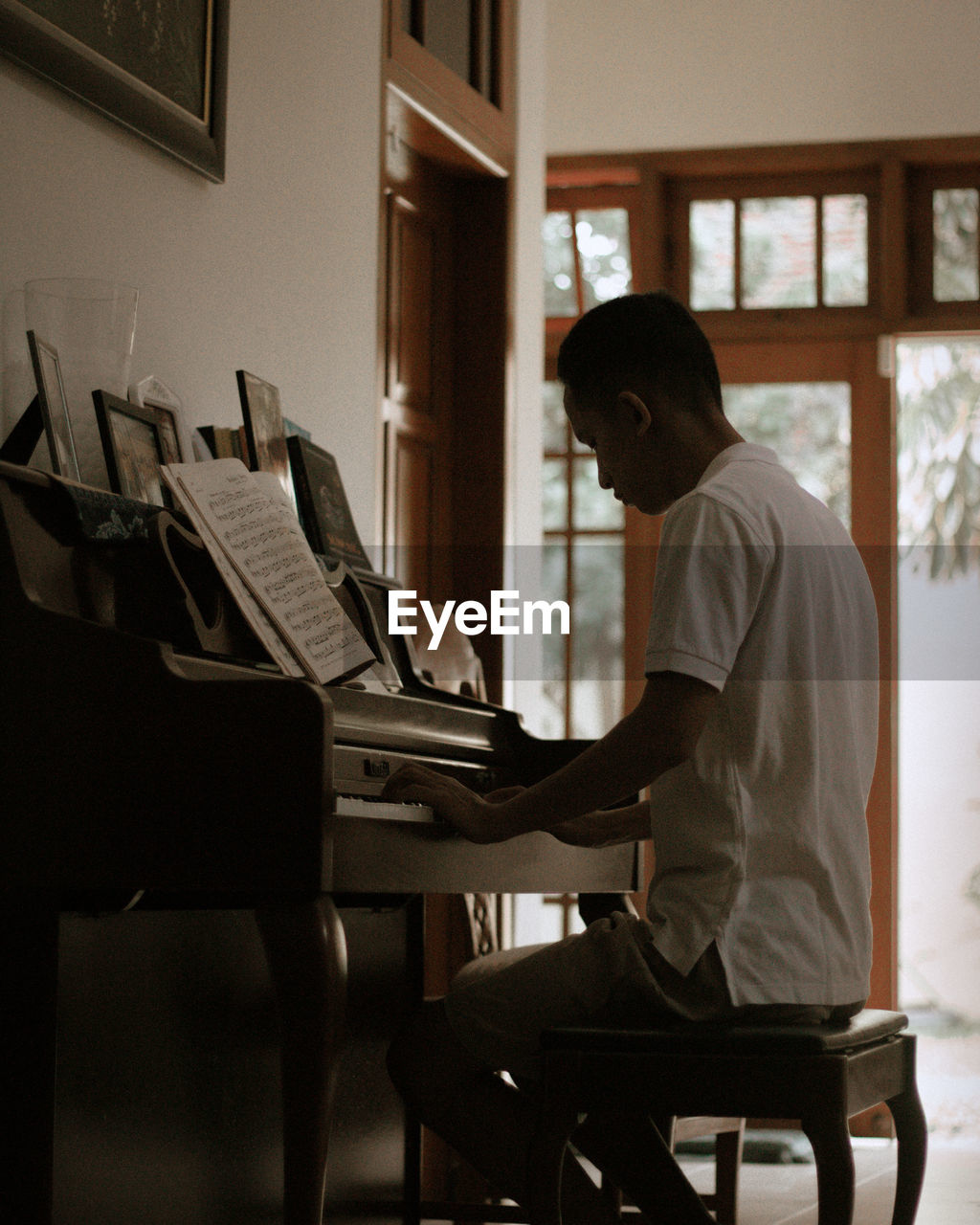 Side view of man playing piano at home