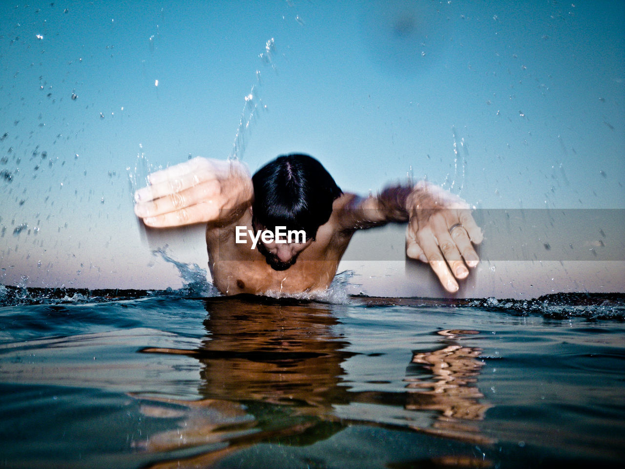 Man diving in lake against blue sky during sunset