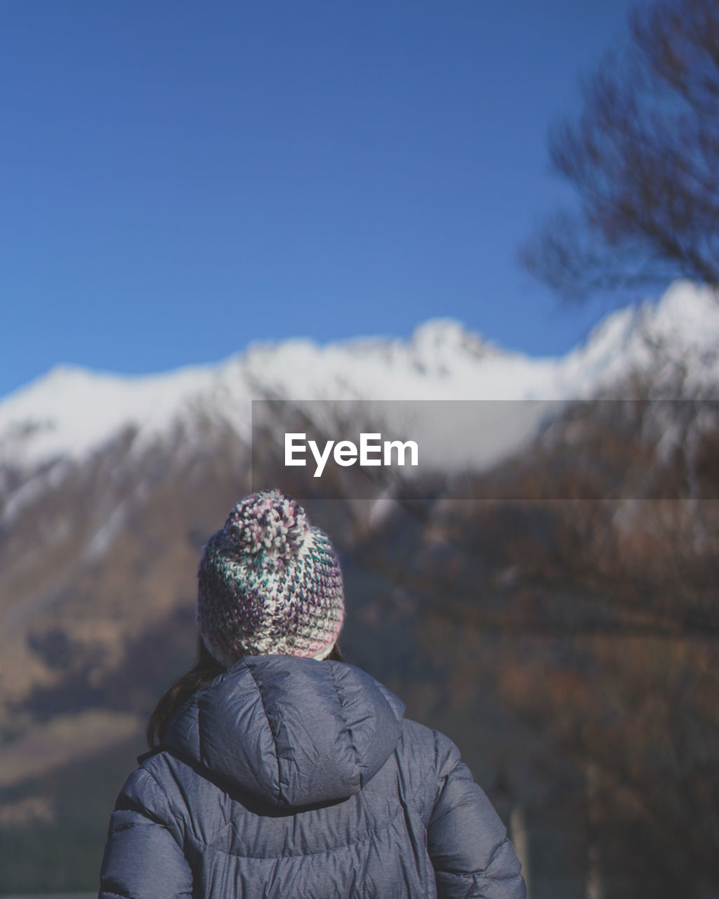 REAR VIEW OF MAN IN SNOW AGAINST SKY