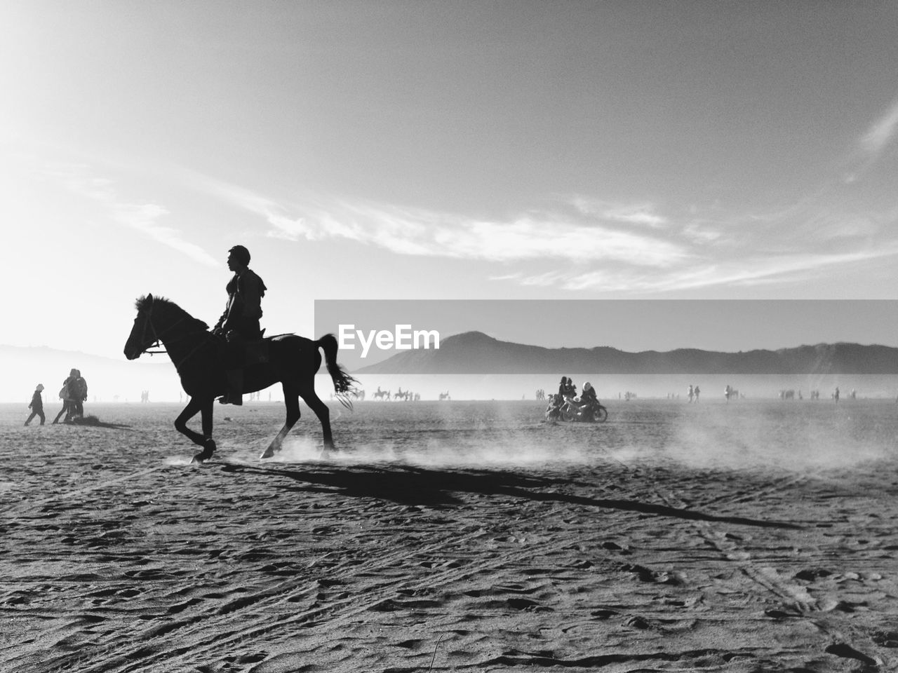 Side view of man riding horse on sand of bromo crater