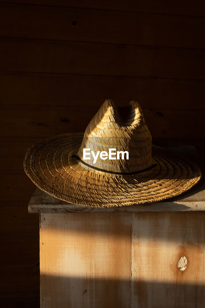 Straw hat under sunlight on wooden table