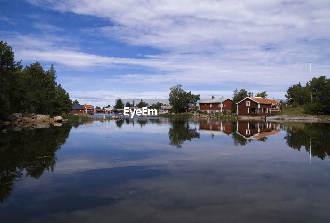 Houses by lake and buildings against sky