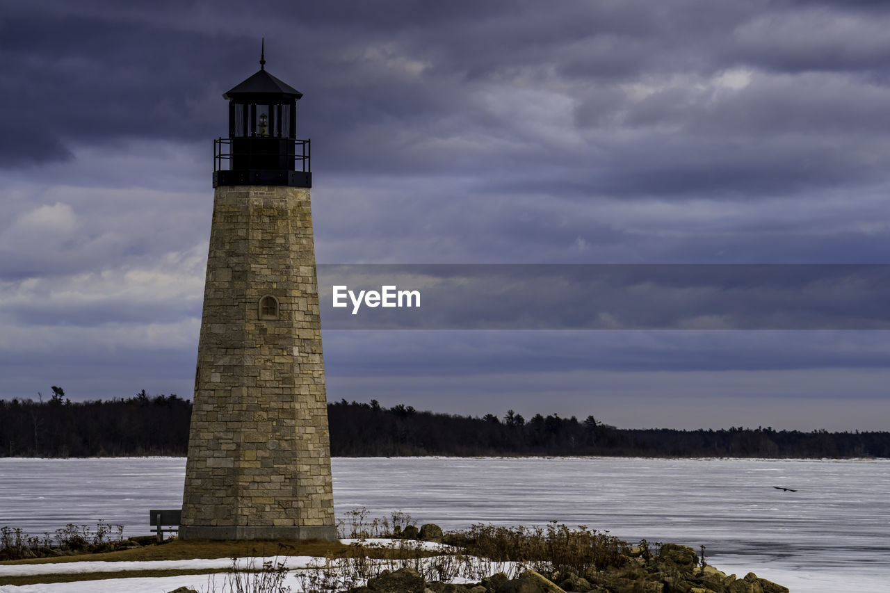 lighthouse, tower, architecture, water, built structure, guidance, sky, cloud, building exterior, building, nature, environment, sea, beach, security, land, protection, reflection, no people, travel destinations, landscape, scenics - nature, travel, outdoors, history, storm, beauty in nature, the past, coast, observation tower, coastline, day, cold temperature, non-urban scene, snow, plant, winter, dramatic sky