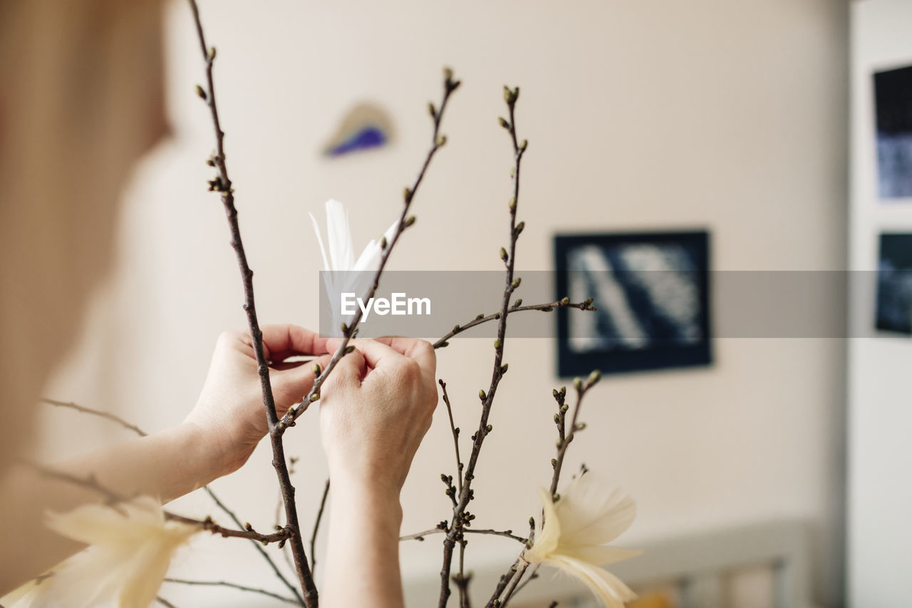 Hands decorating twigs with feathers