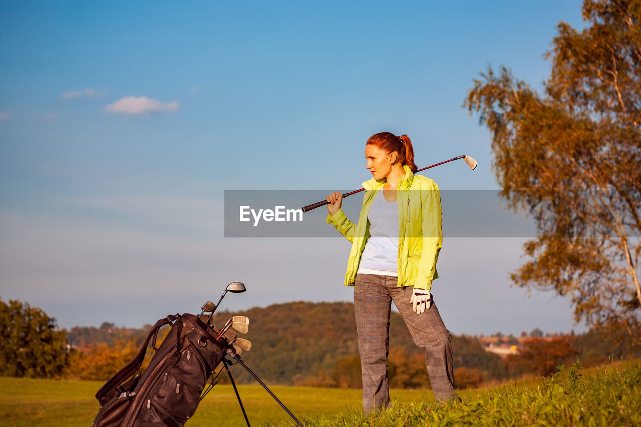 Person holding umbrella on field against sky