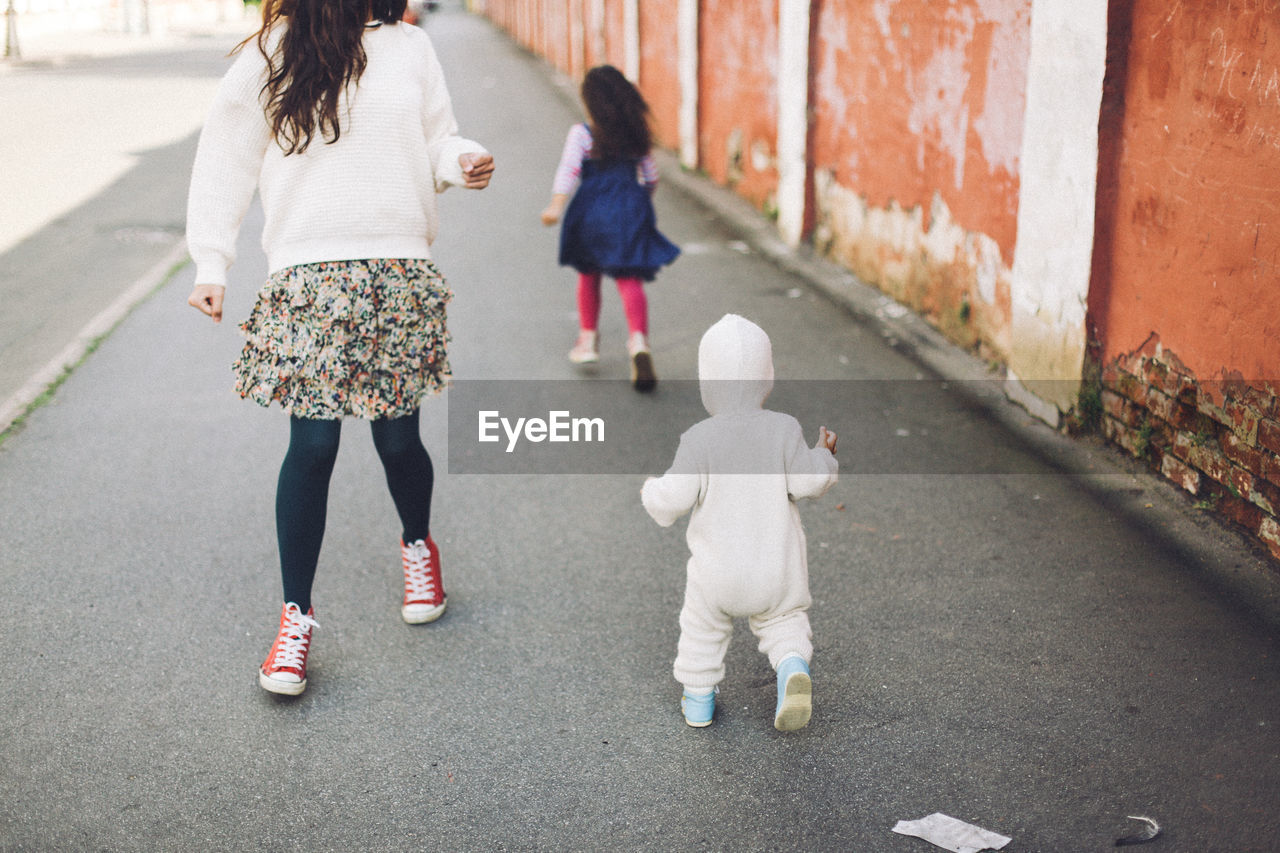 Rear view of mother and children walking on street