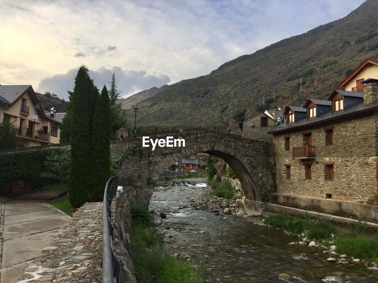 Arch bridge amidst buildings and mountains against sky