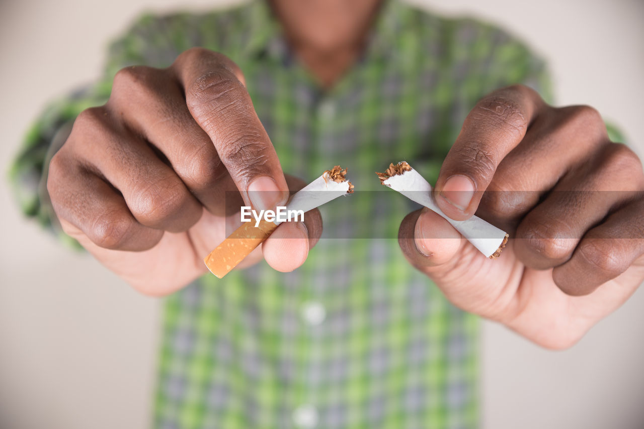 Midsection of man holding cigarettes