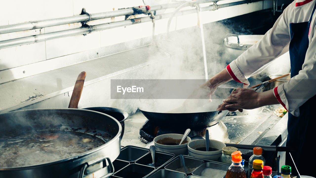 Chef stir fry in wok. professional cooking in kitchen