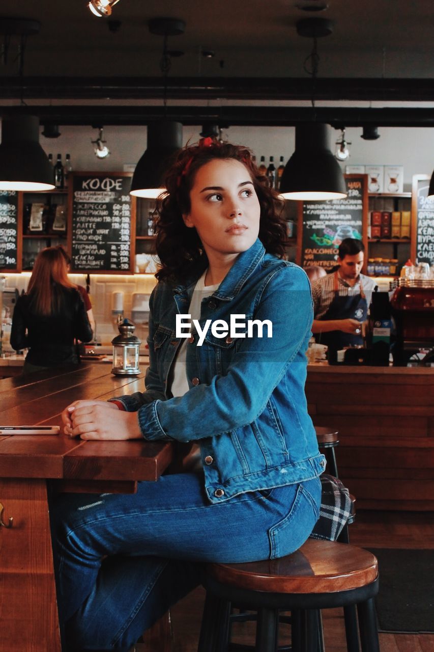 PORTRAIT OF WOMAN SITTING AT RESTAURANT TABLE