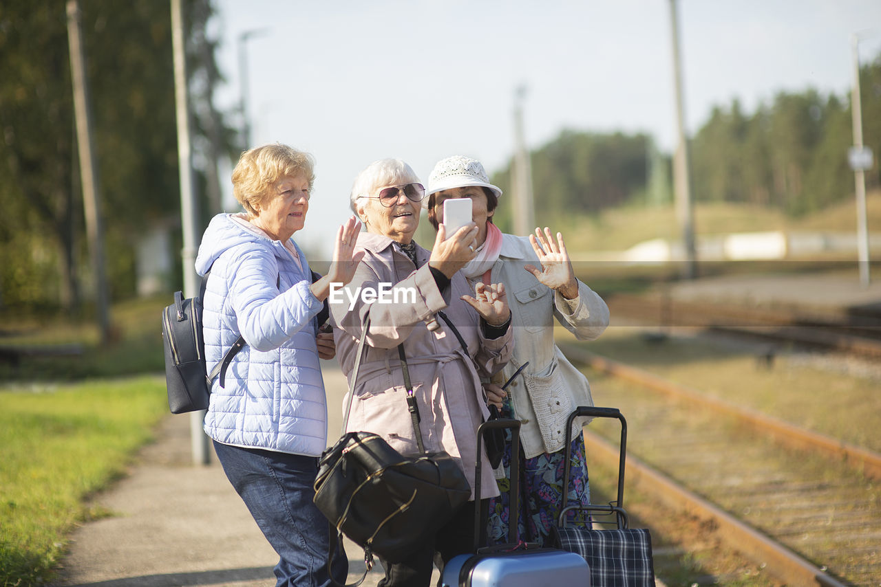Group of smiling  seniors  women take a self-portrait on a platform waiting for a train 