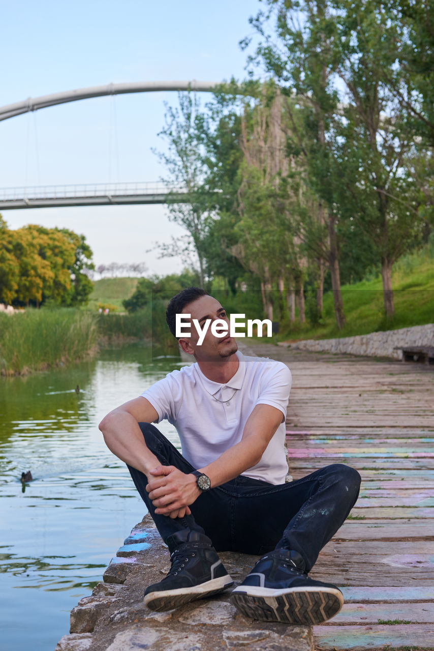 portrait of young man sitting on lake