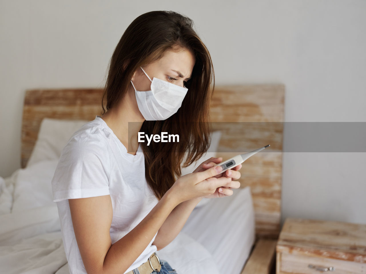 Young woman using mobile phone while sitting on bed