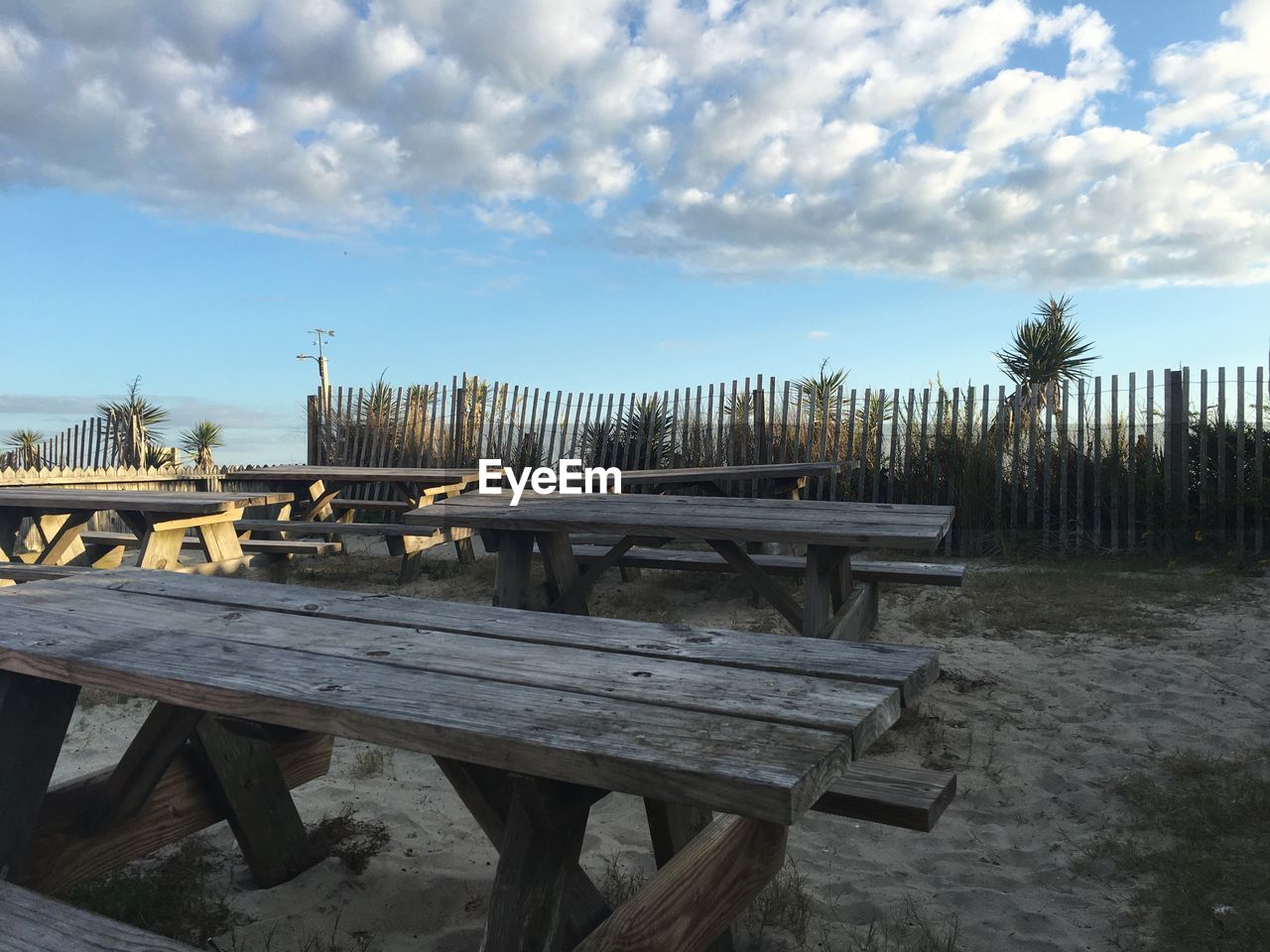 Picnic tables against cloudy sky