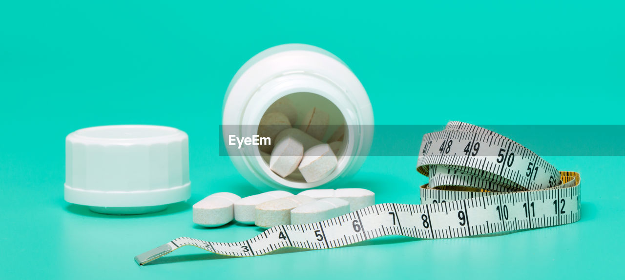 Close-up of pills and tape measure on green background