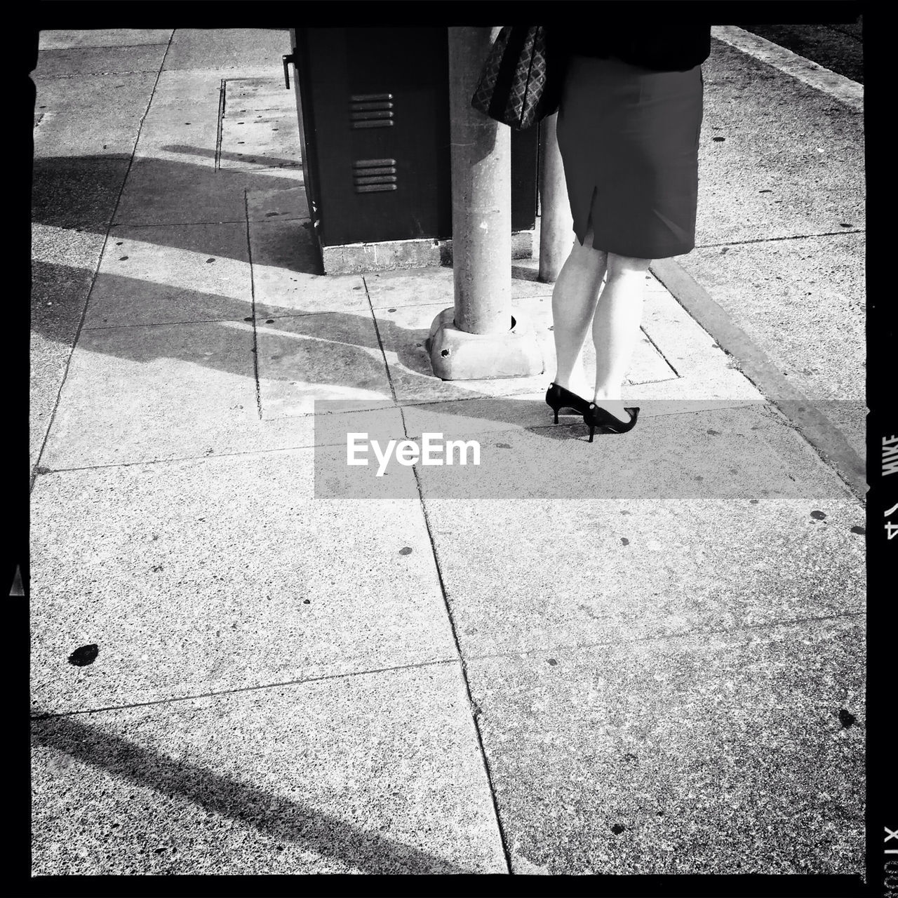 Low section of woman standing on sidewalk