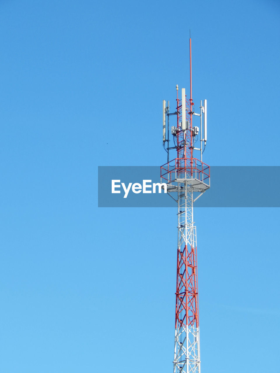 Low angle view of communications tower against clear blue sky