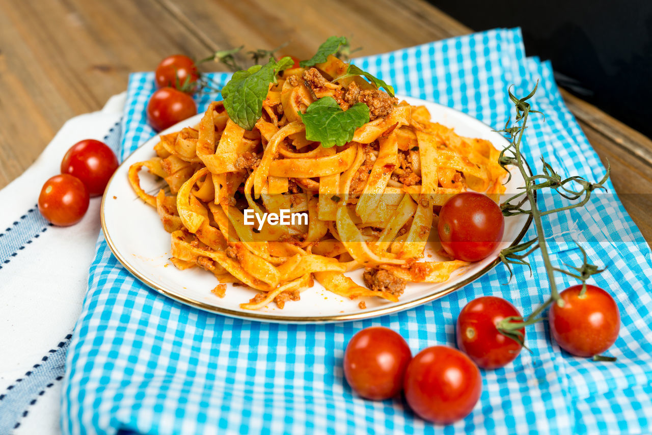 Fresh tagliatelle pasta with tomatoes on table