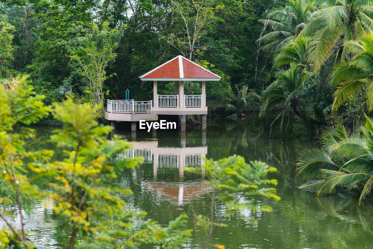 HOUSE BY PALM TREES AGAINST LAKE