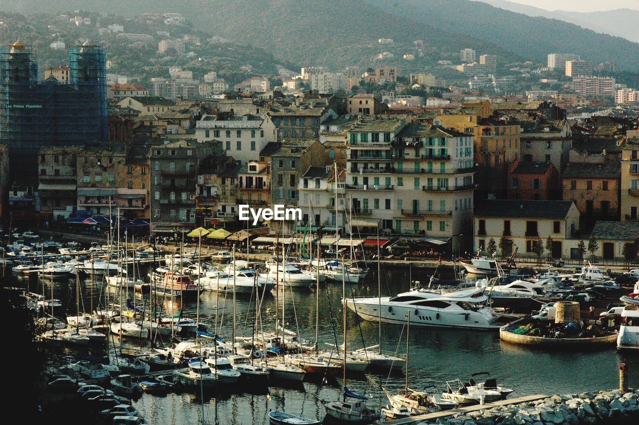 Boats moored in harbor by buildings in city