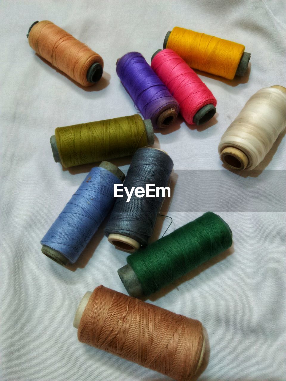 High angle view of colorful thread spools on textile