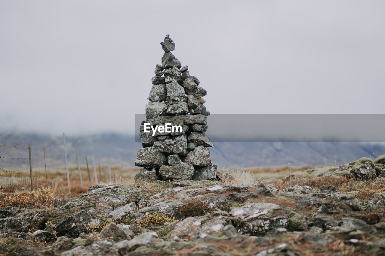 Stacked stones on field against sky