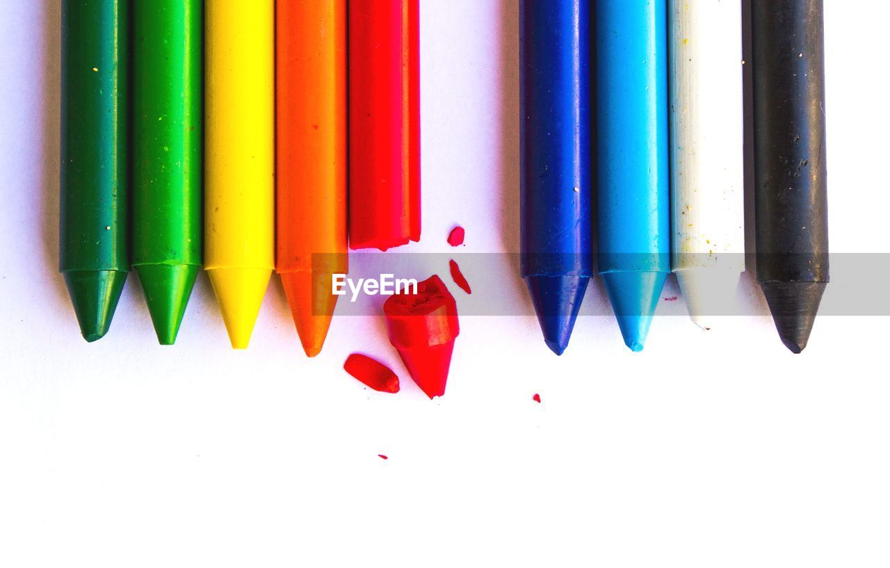 Close-up of colored crayons over white background
