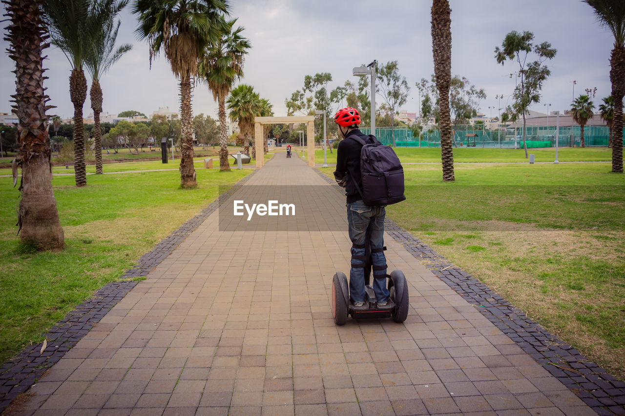 Rear view of man on push scooter at park