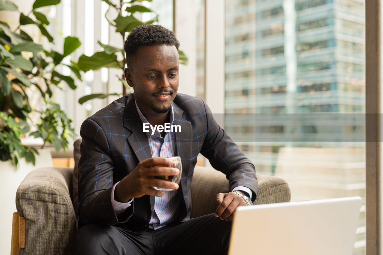 side view of young man using digital tablet while sitting on table