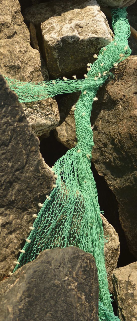 Close-up of fishing net lying in rocks