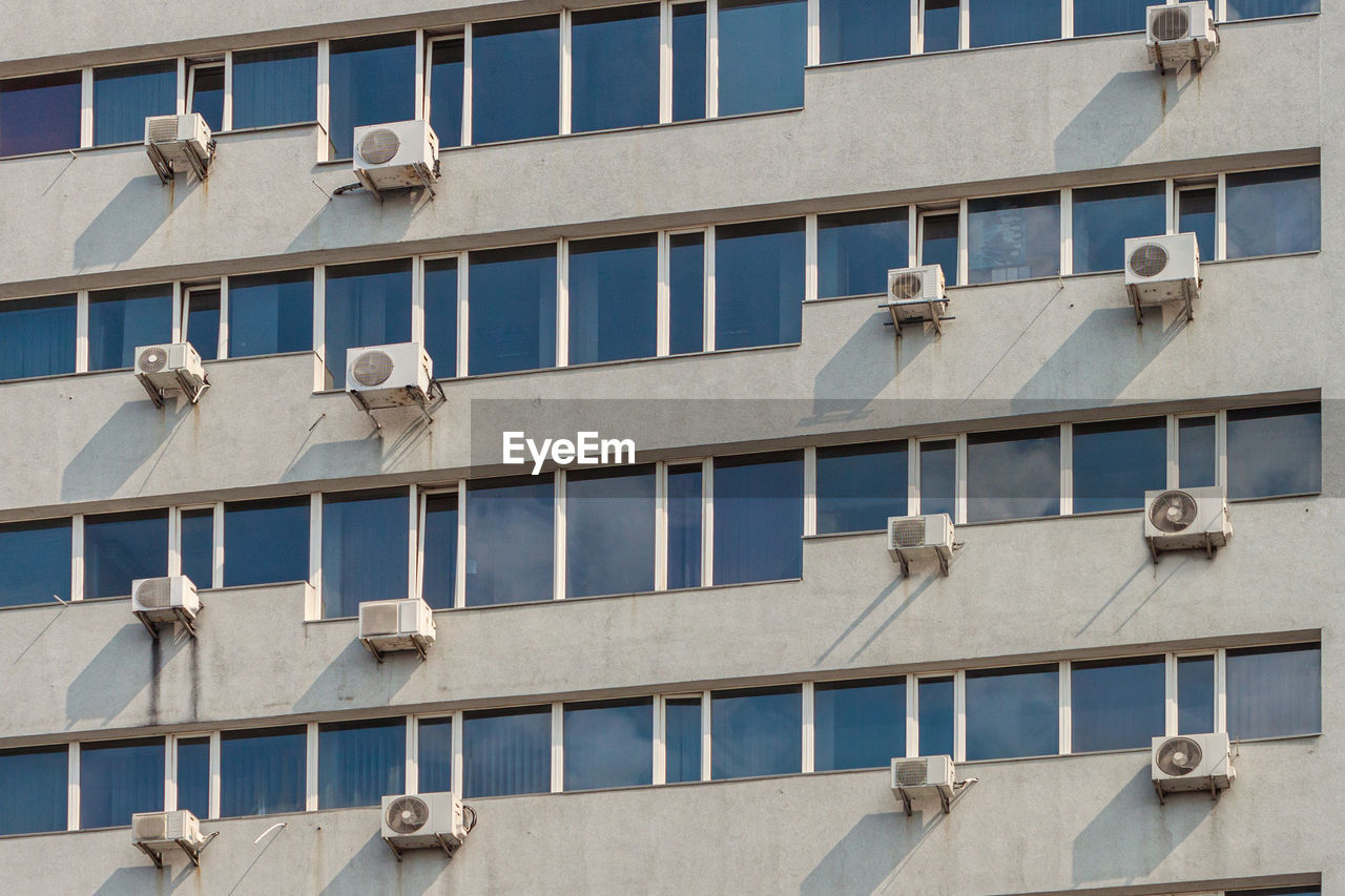 Lots of air conditioners on the wall of the building