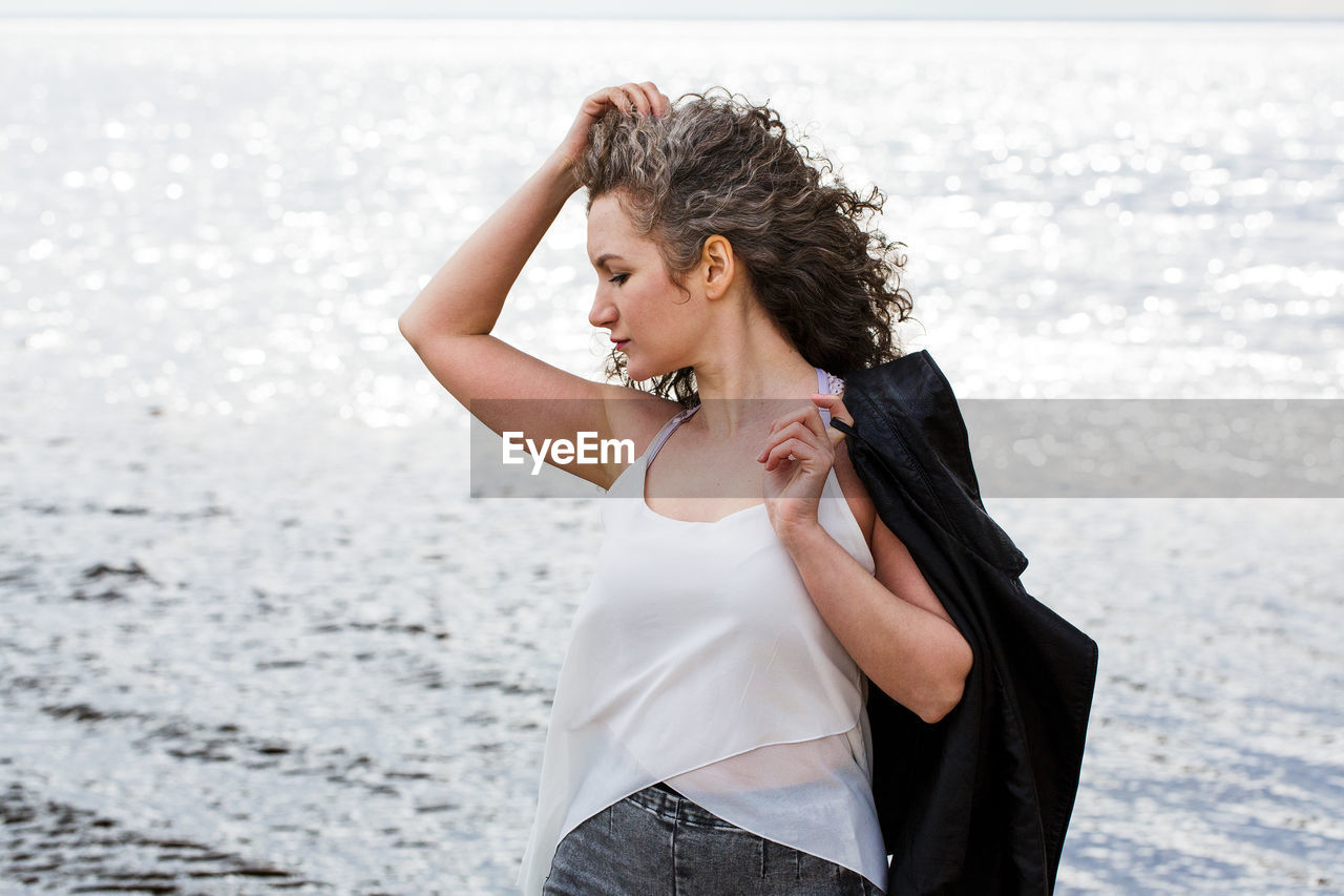 Portrait of a sad curly-haired woman by the sea