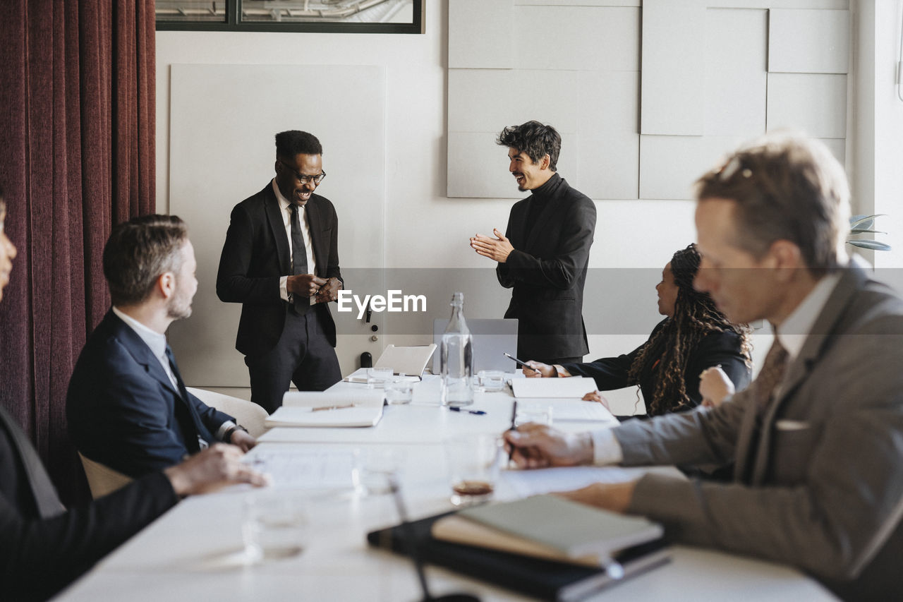 Happy male entrepreneurs discussing during business meeting at office