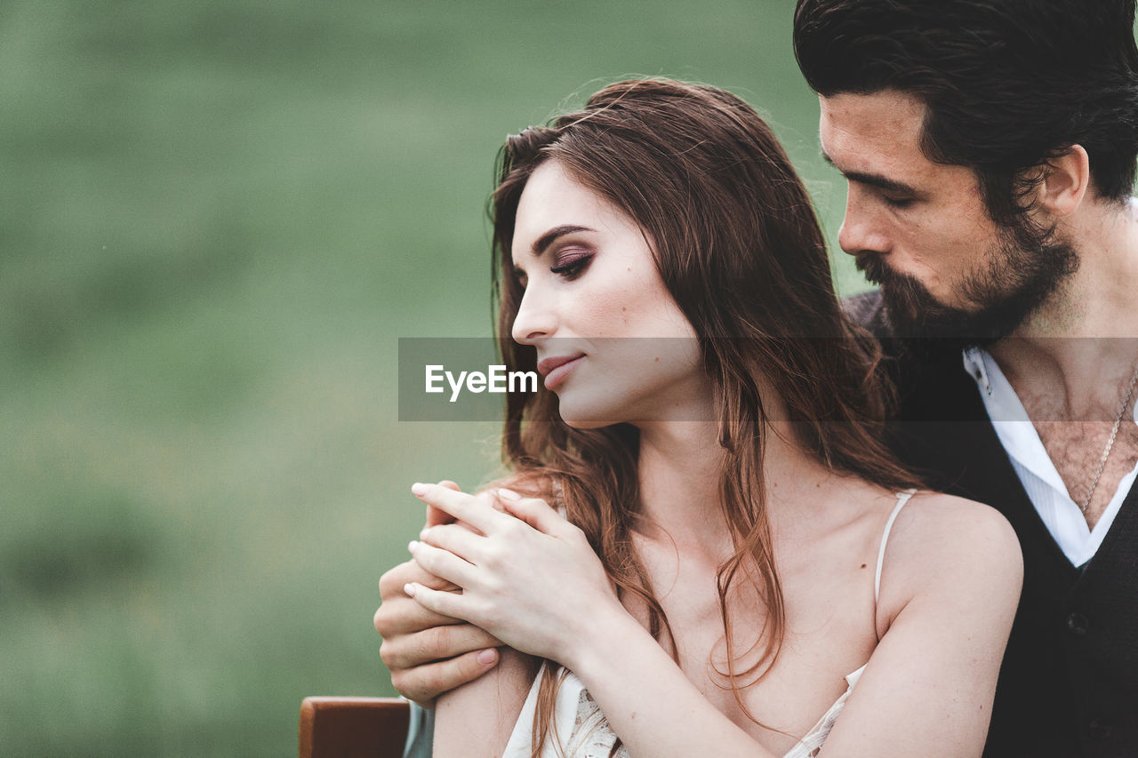 Close-up of wedding couple romancing on field