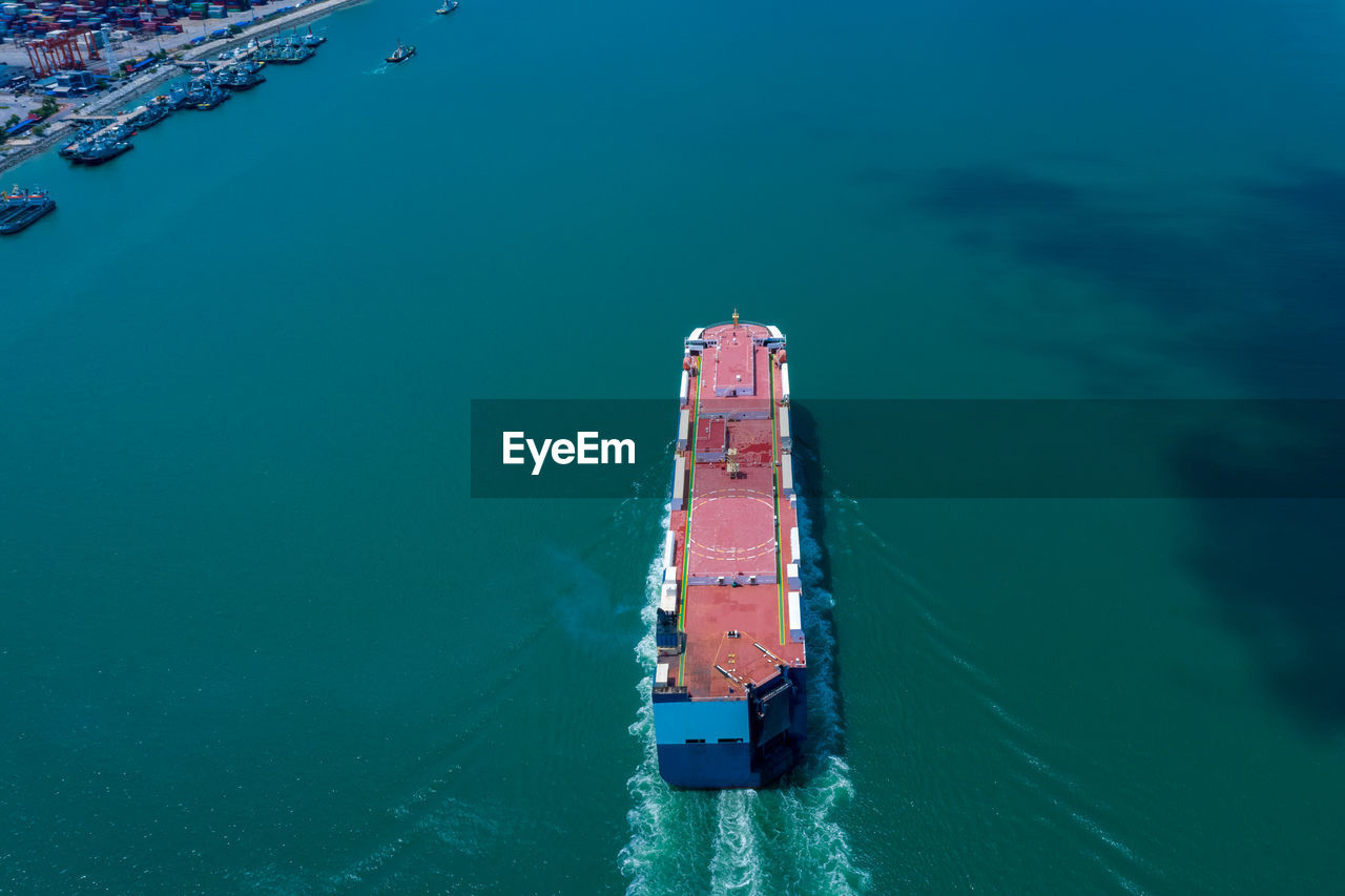 Aerial view ro-ro ship loading new cars. automotive container carriers sailing on the sea 