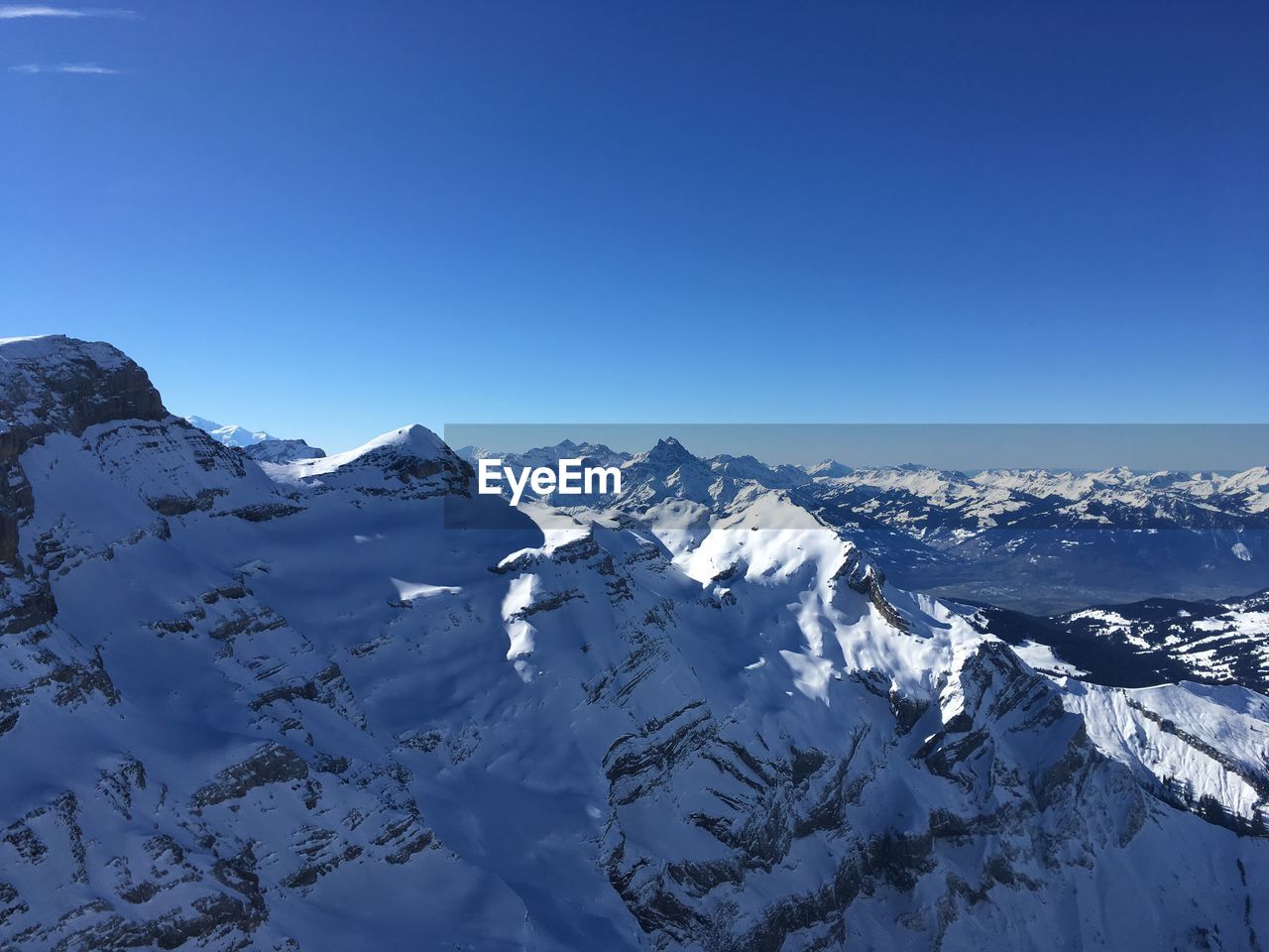 Scenic view of snowcapped mountains against clear blue sky