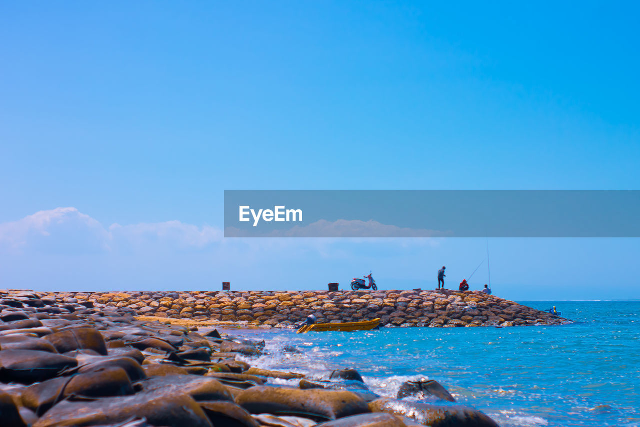 ROCKS ON BEACH AGAINST BLUE SKY