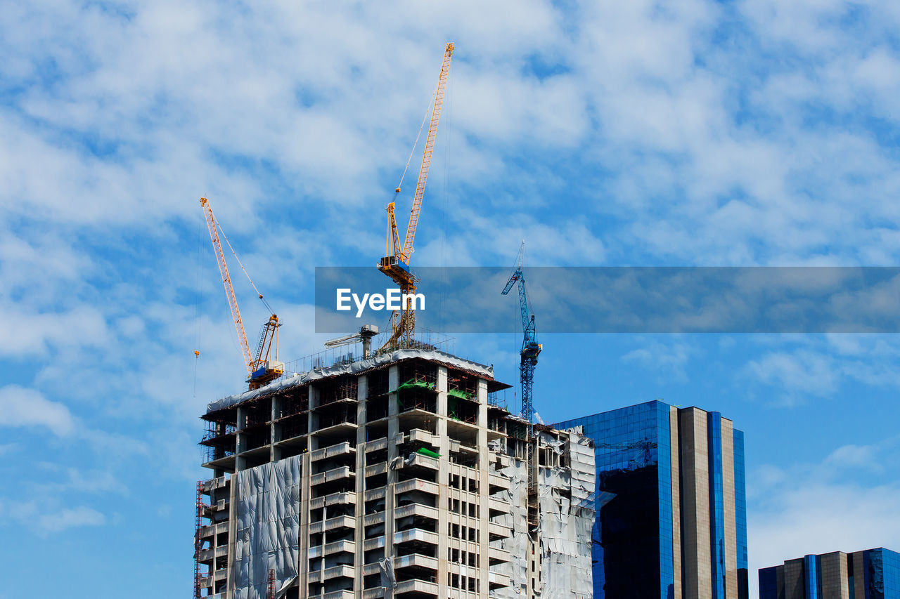 LOW ANGLE VIEW OF CRANE AGAINST BUILDING