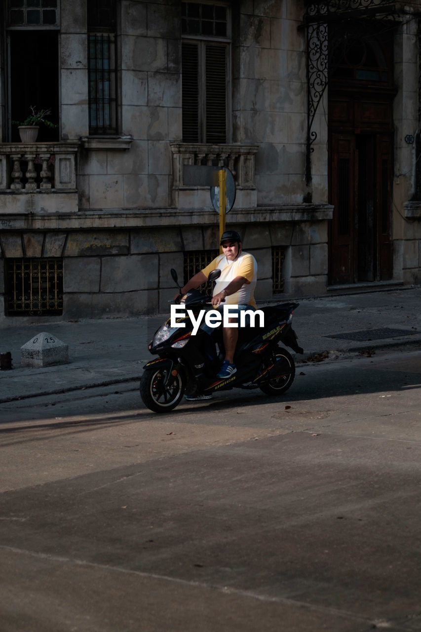 SIDE VIEW OF MAN RIDING SCOOTER ON STREET