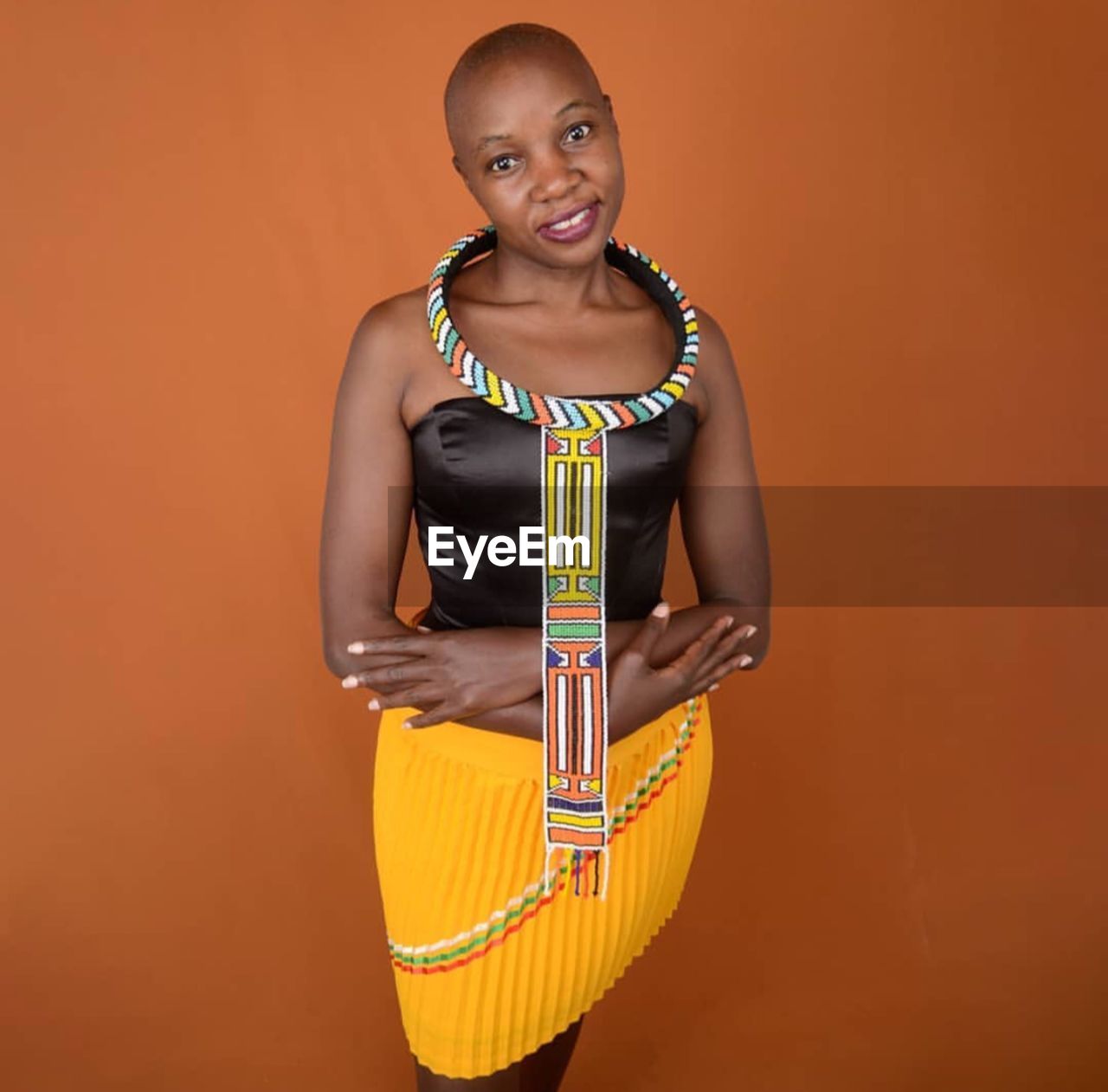 Portrait of young woman standing against yellow background