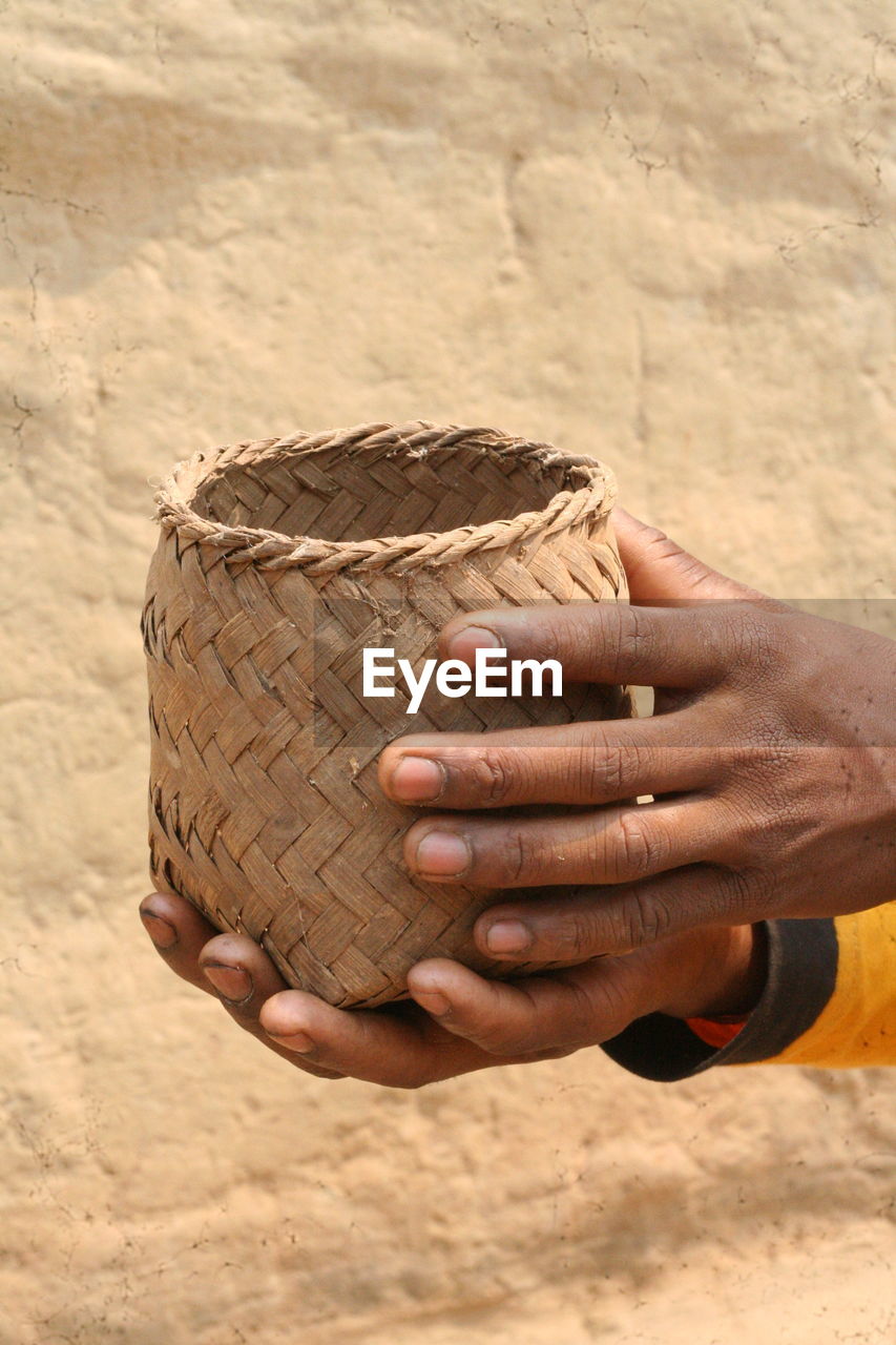 Cropped hand of man holding a handwoven basket