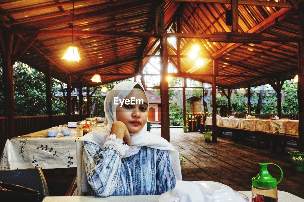 PORTRAIT OF YOUNG WOMAN SITTING AT RESTAURANT